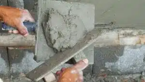 A man constructing a wall using a cement block.