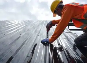 A construction worker installing a metal roof.