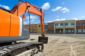 An excavator at a construction site in front of a school building