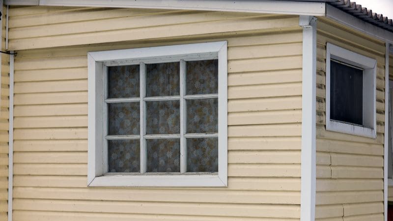 Exterior view of an old wooden house with a white-framed window.