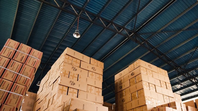 Warehouse with large stacks of cardboard boxes under a metal roof